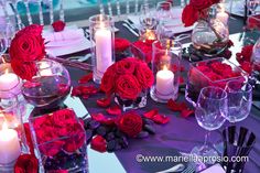 the table is set with red roses and candles