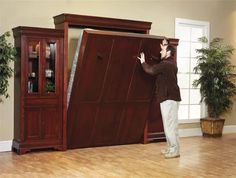 a man standing in front of a large wooden cabinet with its door open and it's bottom panel missing