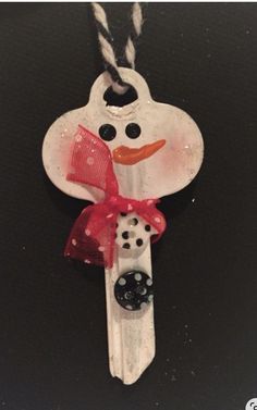 a snowman ornament hanging on a black table with red ribbon and bow