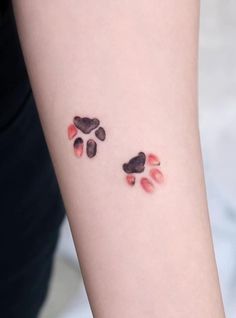 two paw prints on the arm of a woman's left arm, both with red and black spots