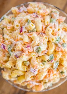 macaroni salad in a glass bowl on a wooden table, ready to be eaten