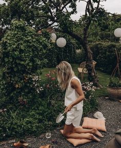 a woman standing in the middle of a garden holding a frisbee and looking at it