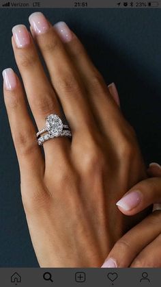 a woman's hand with two engagement rings on her left and the other hand is holding