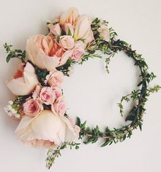 flowers arranged in the shape of a wreath on a white background with greenery around it