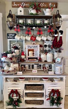 an old dresser decorated for christmas with mugs and wreaths on the front door