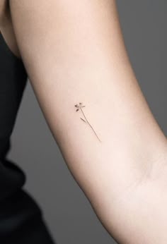 a woman's arm with a single flower tattoo on the left side of her arm