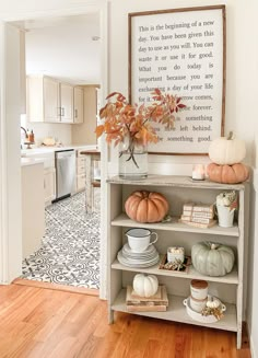 a white shelf filled with plates and pumpkins on top of a hard wood floor