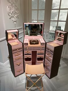 an assortment of pink and black jewelry boxes with mirrors on the top, two folding stools in front of them