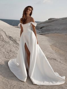 a woman in a white dress standing on the beach