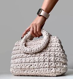 a hand holding onto a white crocheted purse