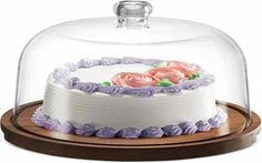 a cake under a glass dome on a wooden stand with pink and purple frosting