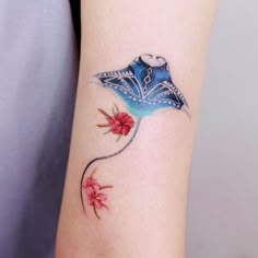 a woman's arm with a blue and red tattoo design on the left side of her arm