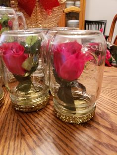 three glass vases with roses in them sitting on a table