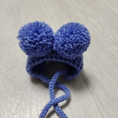 a crocheted blue hat with two pom - poms