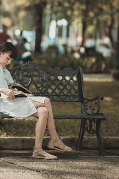 a woman sitting on a bench reading a book