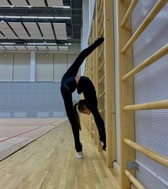 a woman doing a handstand on the floor in an empty gym with hard wood floors