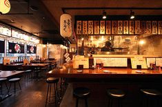 the interior of a japanese restaurant with wooden tables and stools in front of it