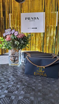 a table with flowers and purses on it in front of a gold curtain backdrop