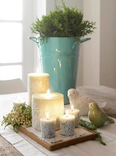 three lit candles sitting on top of a wooden tray next to a potted plant