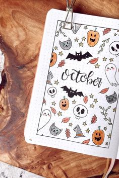 an open notebook with halloween stickers on it next to a cup of coffee and cookies