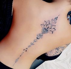 a woman's lower back tattoo with flowers and leaves on her left side ribcage