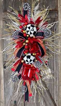 a red, black and white christmas wreath hanging on the side of a wooden door