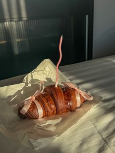 a croissant wrapped in pink ribbon sitting on top of a white table cloth