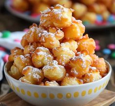 a white bowl filled with powdered sugar covered donuts on top of a wooden board