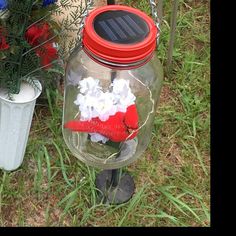 a glass jar with flowers in it and a solar panel attached to the lid sitting next to a flower pot