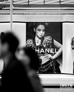 two women are standing in front of a chanel advertisement