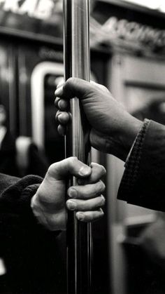 two hands are holding onto the handle of a pole on a subway train or bus