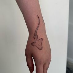 a person's hand with a small tattoo on the left side of their arm