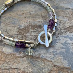 This double stranded bracelet is very pretty and feminine! One strand is populated with small, 3.5mm micro faceted fluorite beads and a sterling silver teardrop sits in the center. Amethyst rondells at the clasp. The other strand is Hill Tribe sterling liquid silver, each one separated with a tiny silver bead. Finished with a Hill Tribe sterling silver toggle clasp and fluorite dangle. Fluorite 3.5 mm / natural Toggle: 12mm / Hill Tribe sterling silver Your jewelry will arrive in a cotton lined Adjustable Double Strand Bracelet With Faceted Beads, Adjustable Double Strand Bracelets With Faceted Beads, Silver Double Strand Beaded Bracelets With Gemstones, Silver Double Strand Bracelets With Gemstone Beads, Silver Double Strand Bracelet With Natural Stones, Silver Multi-strand Spiritual Bracelets, Healing Silver Beaded Bracelets With Faceted Beads, Silver Beaded Bracelets For Healing, Silver Amethyst Beaded Bracelets With Faceted Beads