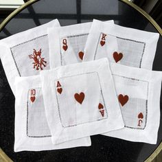 four white napkins with red hearts on them are sitting on a black table in front of a window