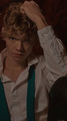 a young man with curly hair wearing suspenders and a white shirt