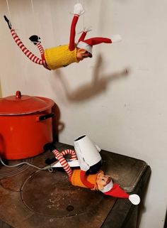 two elf figurines on top of an old table with a pot and pan