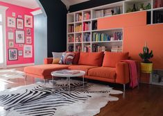 a living room with an orange couch and zebra print rug on the floor in front of a bookshelf