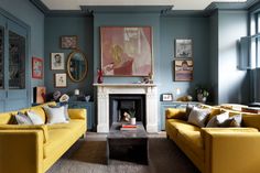 a living room with blue walls and yellow couches in front of a fire place