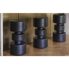 three different types of black vases sitting next to each other on a wooden floor