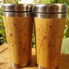 two stainless steel tumblers sitting on top of a wooden table