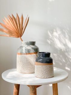 two vases sitting on top of a white table