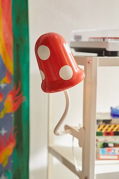 a red lamp sitting on top of a white table next to a green and yellow curtain