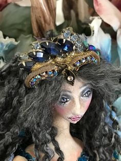 a close up of a doll with long hair and blue eyes wearing a tiara