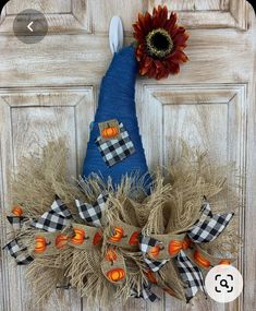 a blue scarecrow door hanger with a sunflower on it and an orange flower