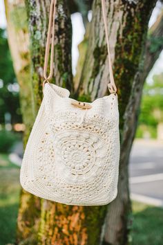 a white crocheted bag hanging from a tree