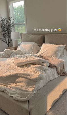 an unmade bed sitting in a bedroom next to a window with the words morning glow on it