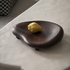 a yellow fruit sitting on top of a wooden plate next to a white tablecloth