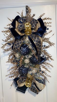 a wreath with blue and gold decorations hanging on the front door to welcome people into the house