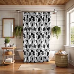 a black and white shower curtain in a bathroom with wood flooring, potted plants on the window sill