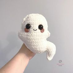 a hand holding a white stuffed animal with eyes